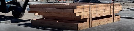 Prefabricated framing components bundled and staged on a jobsite slab